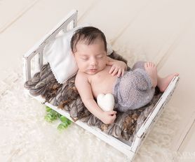 nyfödd baby sover i säng med wool hjärta