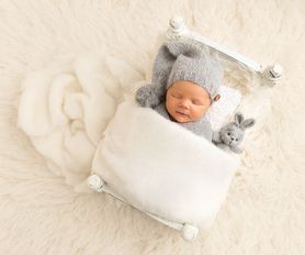 Nyfödd bebis ligger i säng på nyföddfotografering